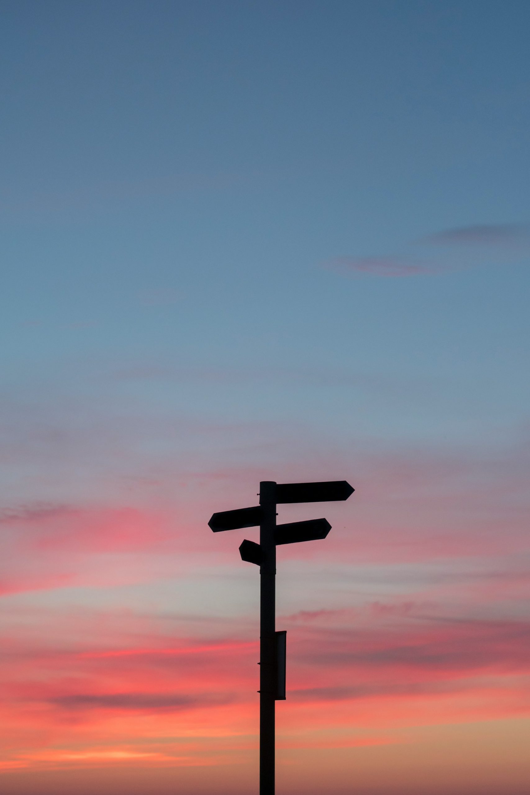 Street signs in silhouette against a sunset