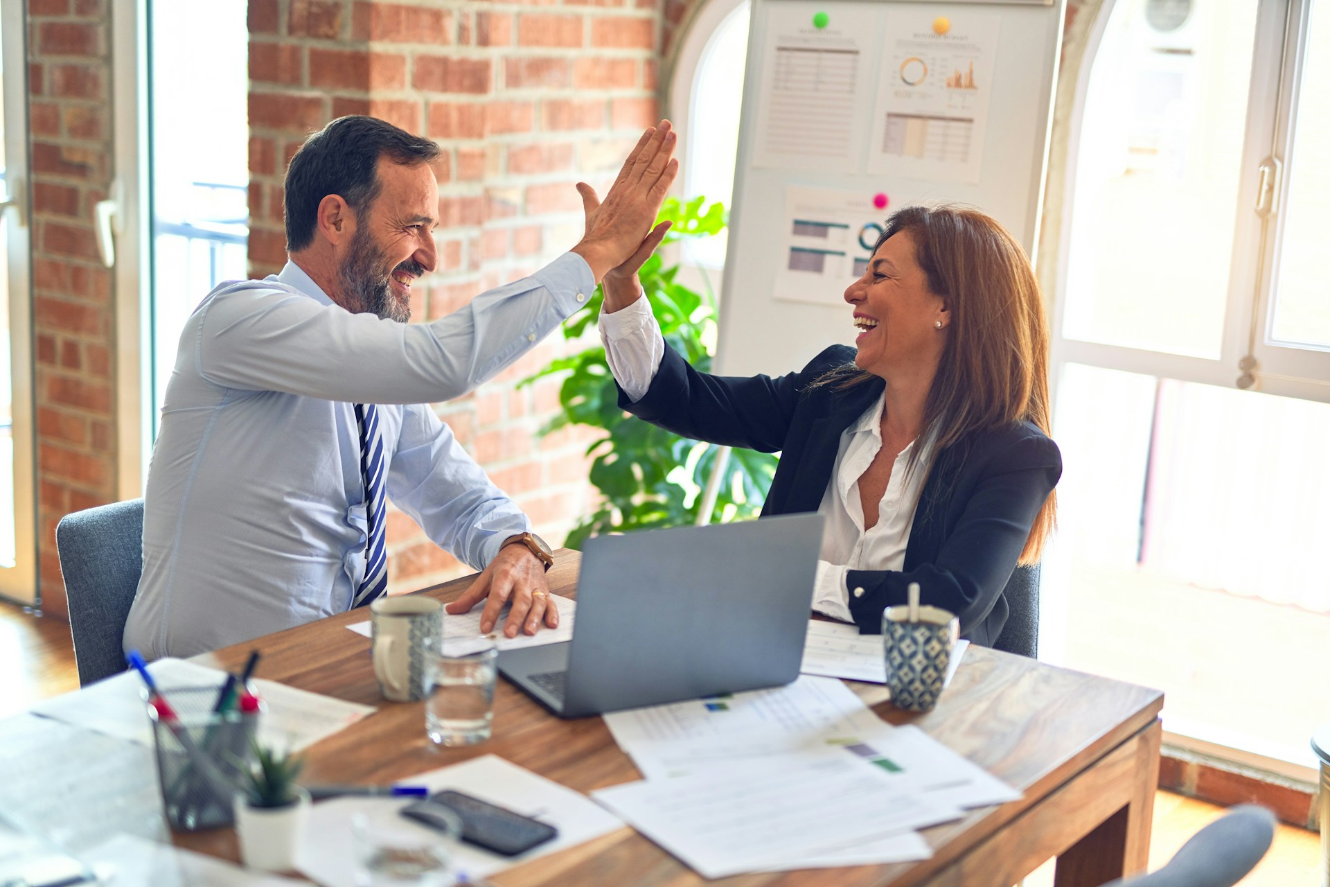 Man and woman in a conference room high fiving each other