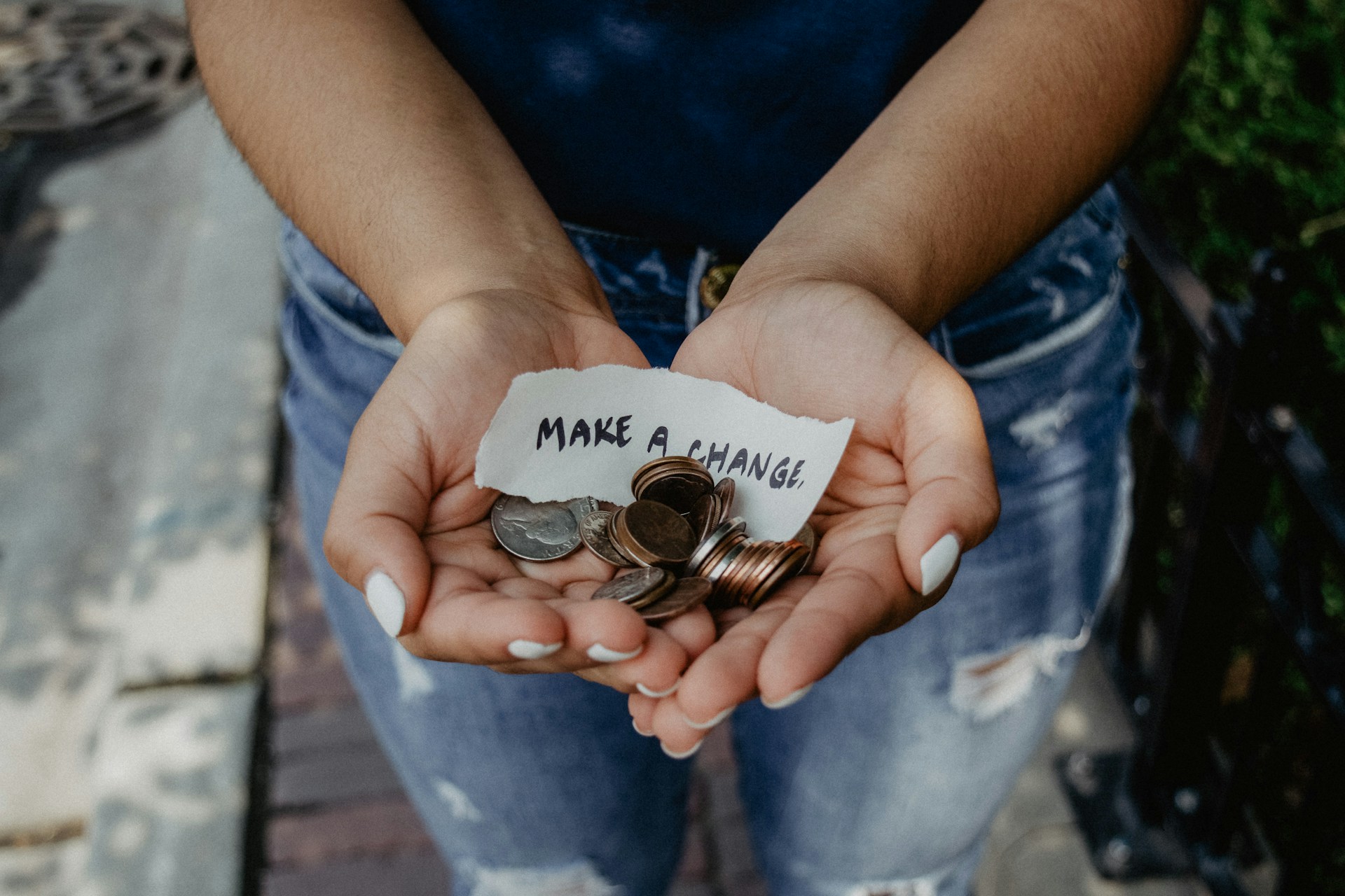 A woman's hands holding coins and a piece of paper saying